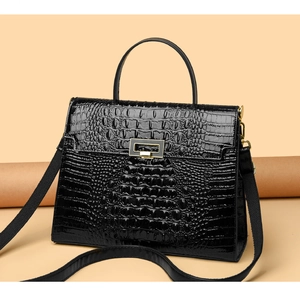 Detail of black crocodile-embossed leather handbag with metallic clasp and shoulder strap