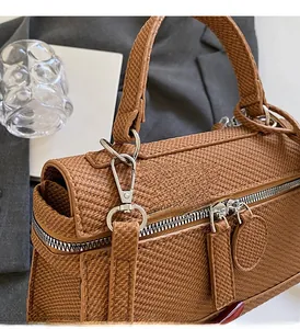 Detail view of woven brown leather handbag with premium silver hardware and double zippers
