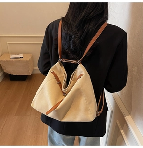 Rear view of woman wearing large canvas tote bag with brown leather straps in warm room
