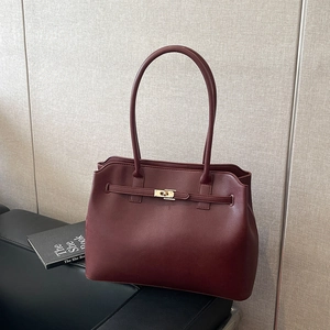 Minimalist burgundy leather tote bag with gold swivel lock and long shoulder straps