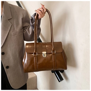 Detail of dark brown retro leather handbag with gold metallic lock and glossy finish