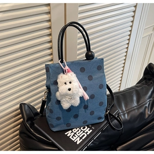 Close-up of blue denim polka dot tote bag with round handle and plush puppy charm