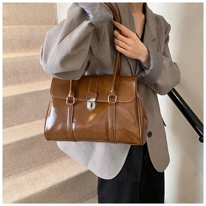Detail of vintage brown glossy leather tote bag with silver metallic buckle on shoulder strap