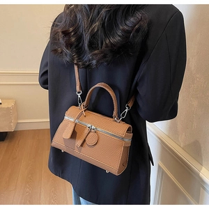 Detail of brown woven texture small square bag worn with a black blazer for office style