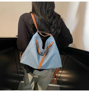 Detail view of denim tote bag with leather straps on model in minimalist setting