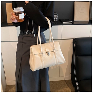 Detail of a beige glossy leather tote bag with silver metal lock for chic office style