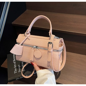 Detailed weave texture of pink crossbody bag with silver zippers on a wooden step