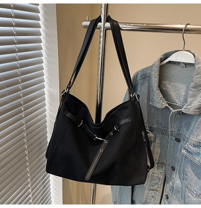 Detail of black canvas tote bag with leather straps and silver metal buckle rings