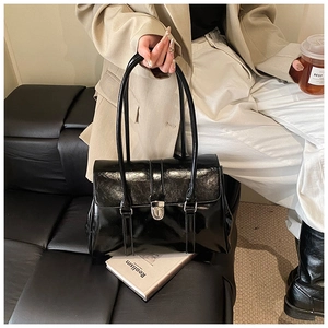Close-up of minimalist black patent leather handbag with silver metallic buckle detail