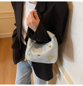 Side view of a light blue patent leather crossbody bag with gold dog charm details