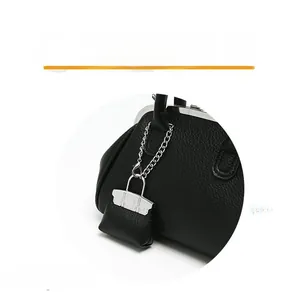 Dettaglio della borsa in pelle nera a grana con hardware argento e mini ciondolo