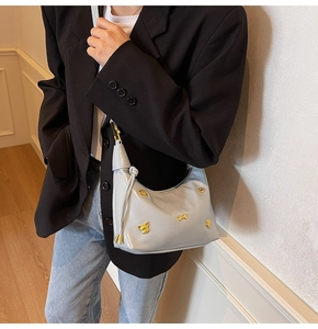 Detail of light blue crescent bag with gold bulldog hardware and leather tassel