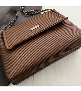 Detail of brown quilted shoulder bag featuring vertical pleats and silver metal buckle closure