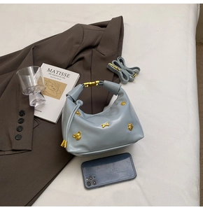 Detail of light blue leather hobo bag with unique gold animal-shaped stud decorations