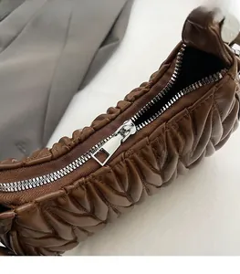 Dettaglio della cerniera in metallo argento e trapuntatura a V sulla borsa in pelle marrone