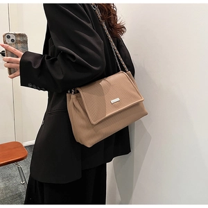 Detail of earthy brown chain shoulder bag featuring fine pleats and metal logo plate