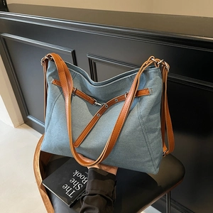 Blue denim tote bag with brown leather straps and metal buckles for casual daily commuting