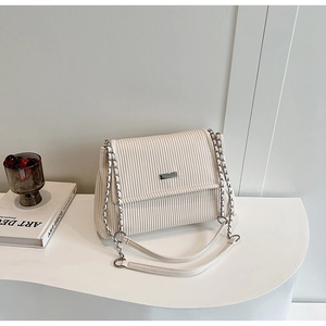 Detail of off-white corduroy shoulder bag with silver chain strap and metal decor