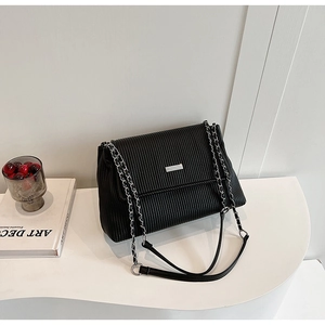 Detailed view of black pleated texture shoulder bag with silver chain strap and metal clasp