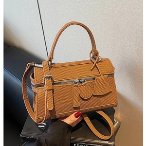 Brown woven crossbody bag with silver hardware and adjustable strap on a book