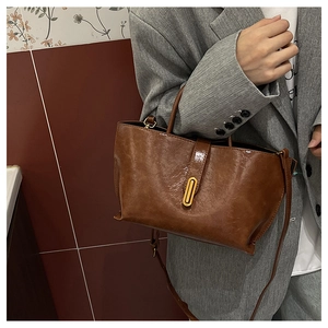 Detail of vintage brown leather tote bag with glossy finish and gold oval metal lock