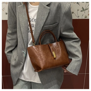 Detail of vintage brown oil-wax leather bucket bag with golden buckle on a model