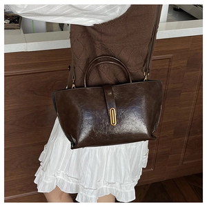 Detail of vintage dark brown oil wax leather handbag with elegant gold metal oval buckle