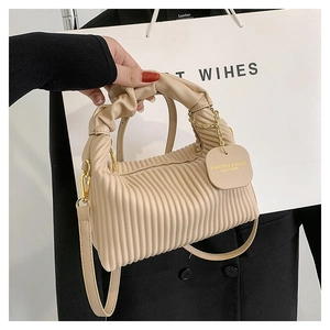 Detailed view of beige pleated handbag texture with logo tag and long shoulder strap