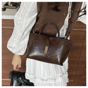 Close-up of vintage dark brown faux leather tote bag with elegant gold metal clasp detail
