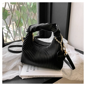 Detail of black pleated handbag with gold chain, cloud handle and detachable shoulder strap