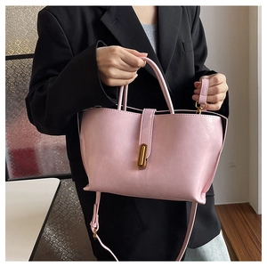 Detailed close-up of a pink tote bag featuring a gold oval twist lock and faux leather texture