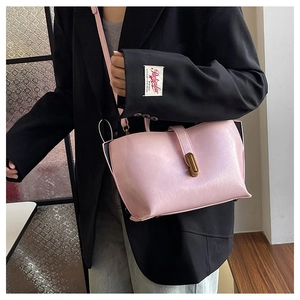 Pink faux leather tote bag with gold clasp and adjustable strap shown on model