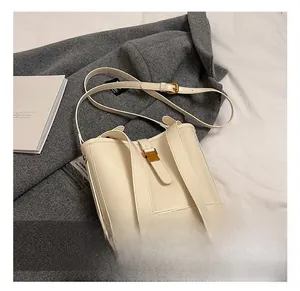 Détail d'un sac seau crème avec boucle dorée sur fond de manteau en laine