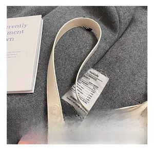 Détail du sac seau en cuir crème montrant les coutures de la bandoulière et la boucle