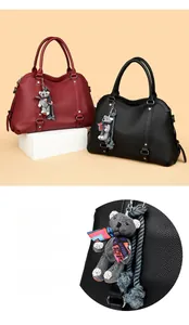 Detail view of lychee pattern leather texture and cute plush bear charm on ladies handbag