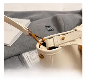 Détails du sac seau en cuir crème avec finitions dorées polies et mousquetons robustes