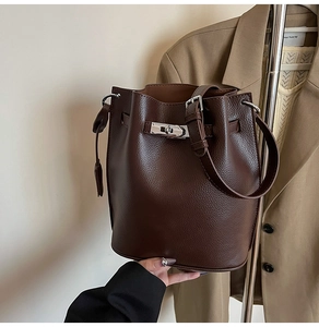 Macro detail of dark coffee lychee grain leather bucket bag with silver lock closure