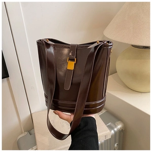 Gros plan d'un sac seau marron foncé vintage avec finition brillante et boucle dorée