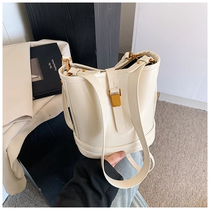 Gros plan du sac seau en cuir crème avec fermoir doré et détails de bandoulière