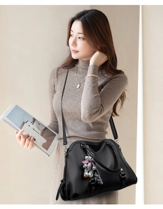 Detail of black lychee texture handbag with plush bear charm and detachable shoulder strap