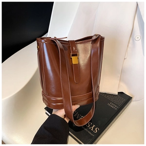 Détail d'un sac seau en cuir marron foncé brillant avec boucle rectangulaire dorée mate