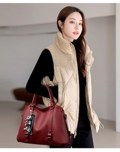 Detail of red litchi texture handbag and beige quilted vest on female model