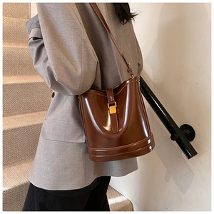 Détail d'un sac seau vintage en cuir verni marron foncé avec boucle dorée en métal
