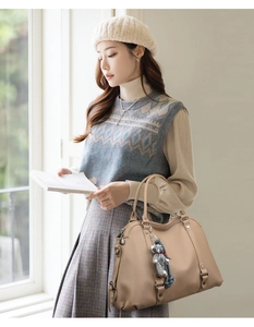 Detail of lychee textured beige tote bag featuring a cute grey plush bear pendant accessory