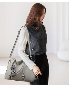 Detail of grey lychee textured leather handbag with detachable strap and teddy bear charm