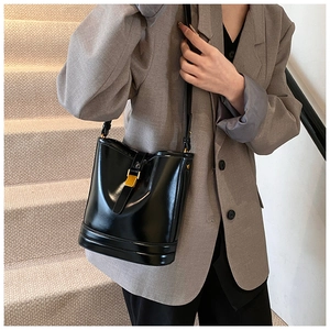 Détail d'un sac seau noir brillant rétro avec fermoir doré sur un mannequin