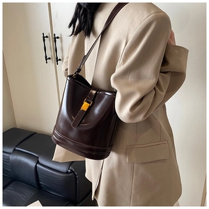 Détail du sac seau vintage marron foncé avec fermoir doré porté sur un blazer beige