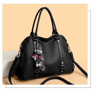Close-up of black lychee grain texture on a tote bag with a cute plush bear charm