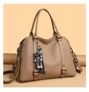 Detail of tan lychee pattern leather tote bag with teddy bear charm and metal rivets