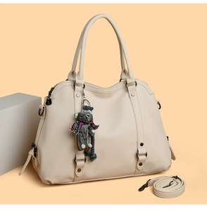 Close-up of cream litchi texture tote bag with bear charm and adjustable shoulder strap